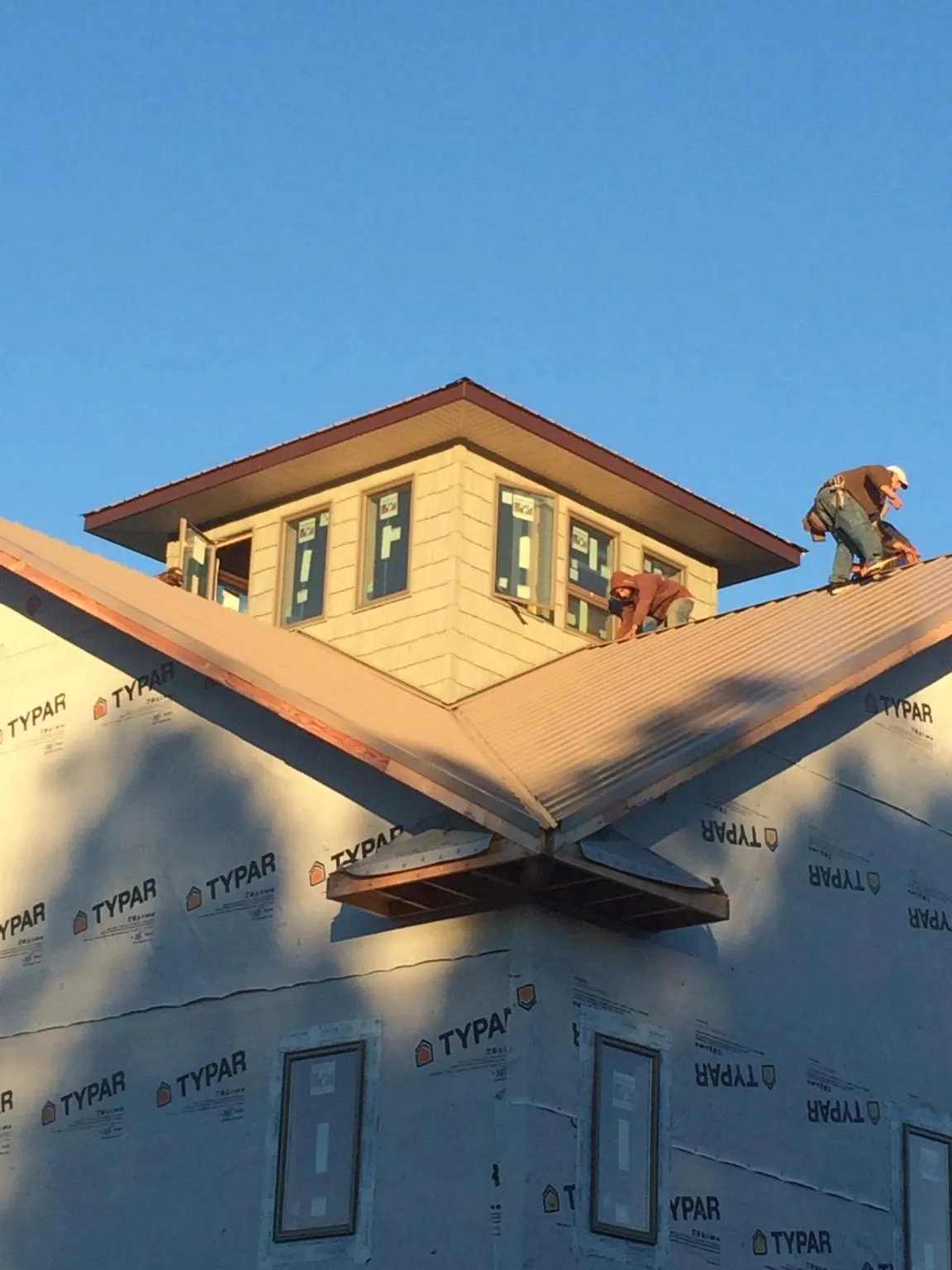 Roofers working around a rooftop cupola on a new metal roof at sunset — Roof Waterproofing in Jackson by Roofing Brothers